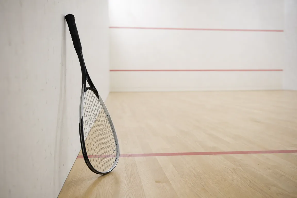 Squashracket som vilar mot väggen i en tom squashbana