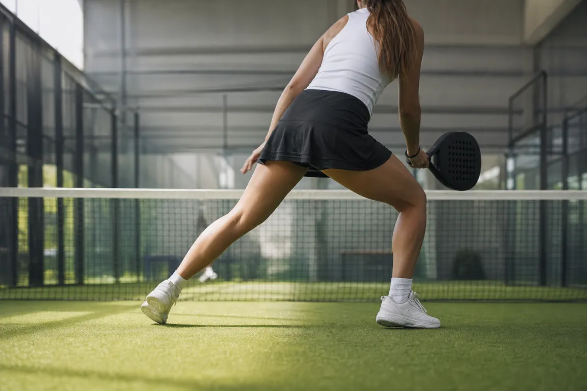 Padelspelare i sidosteg vid nätet med fokus på skorna