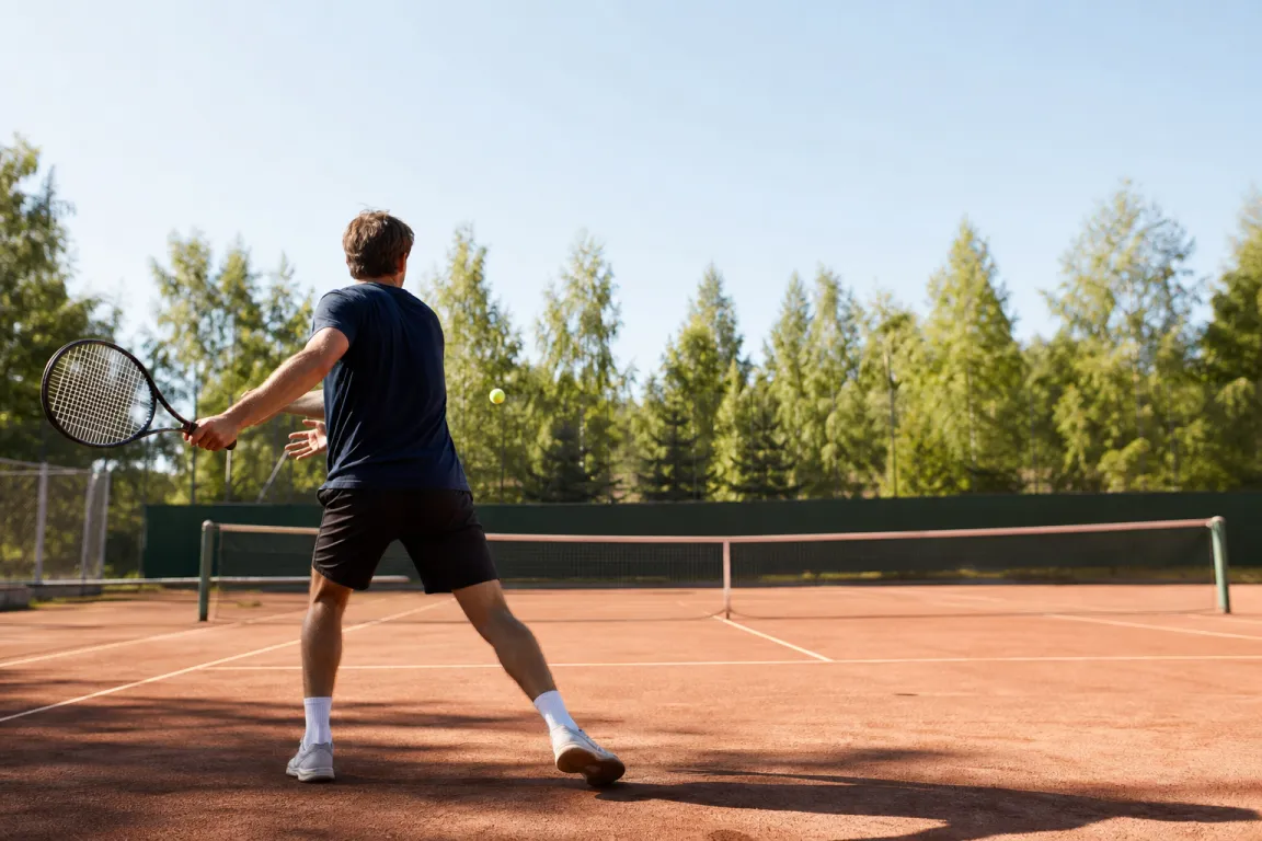 Person sedd bakifrån som svingar ett tennisracket på en utomhusbana